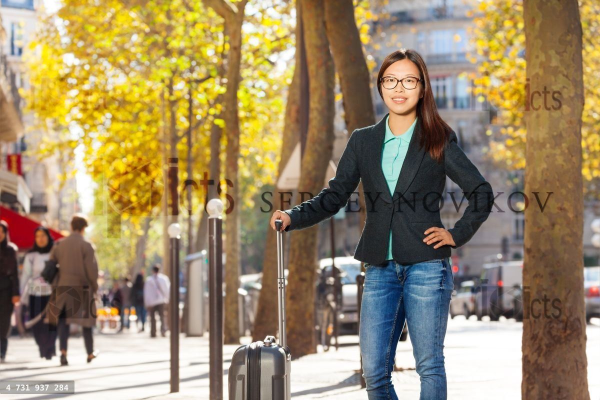 Woman traveling with suitcase standing at street