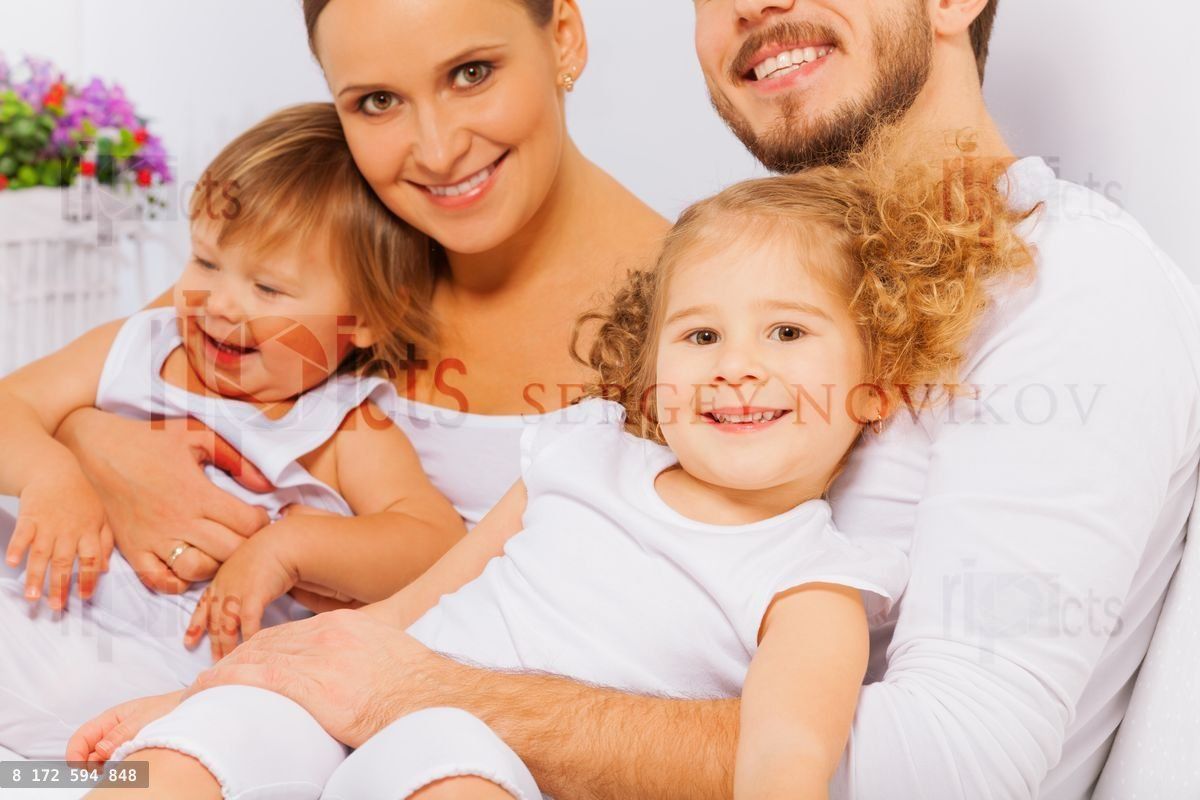 Happy parents with two adorable children on bed