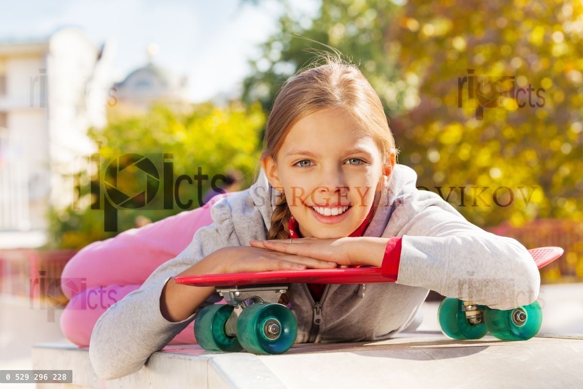Beautiful young lady with arms on red skateboard