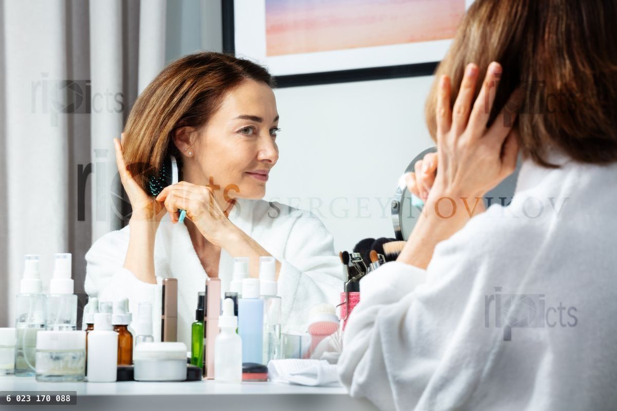 Woman brush hair before makeup mirror at home