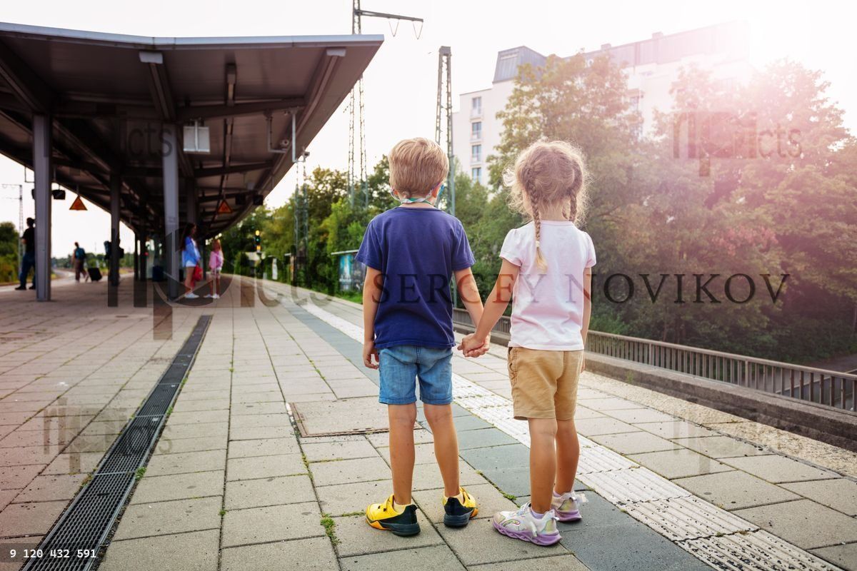Young boy and girl watching a red train arrive at the station