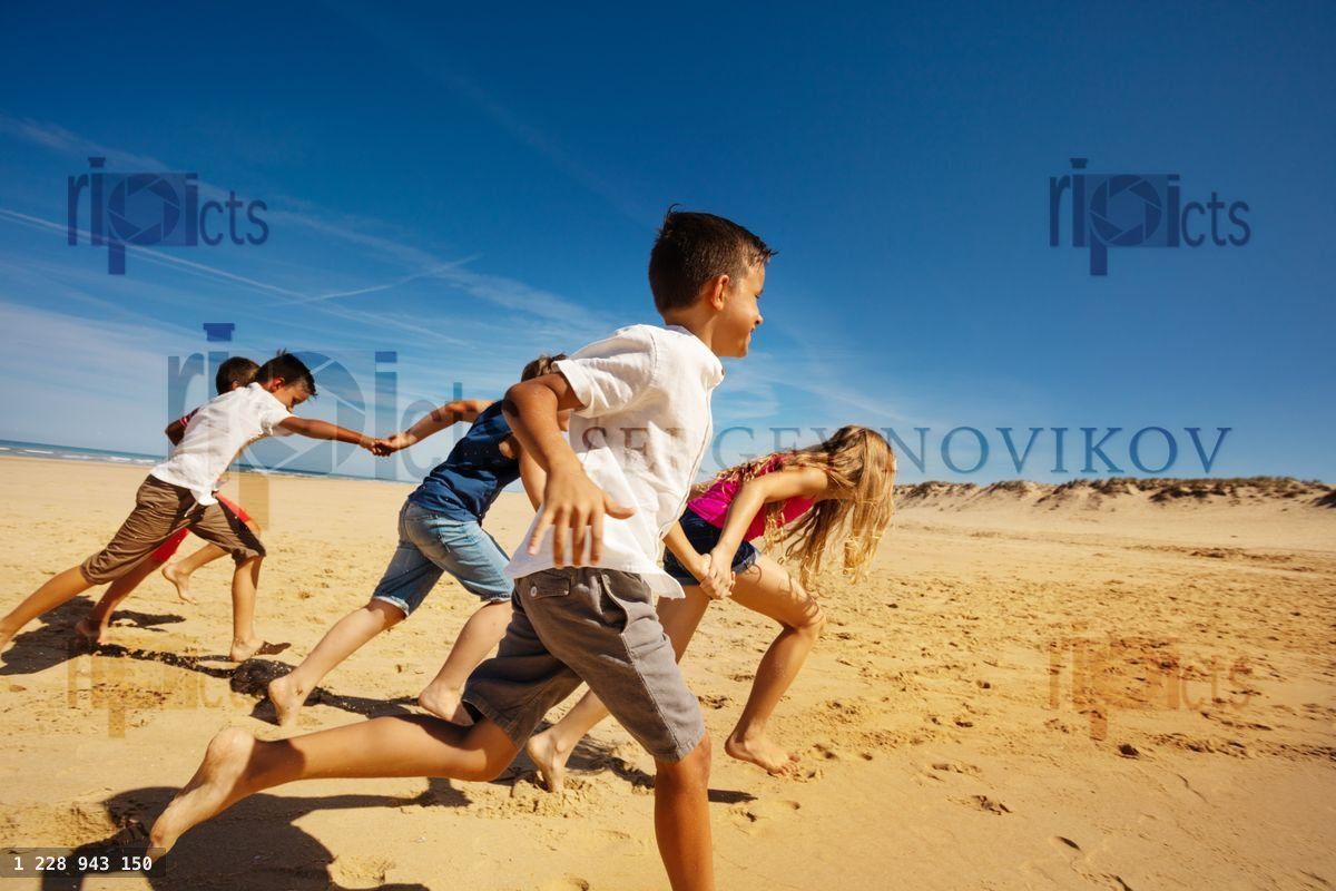 Boys and girls run on the beach holding hands