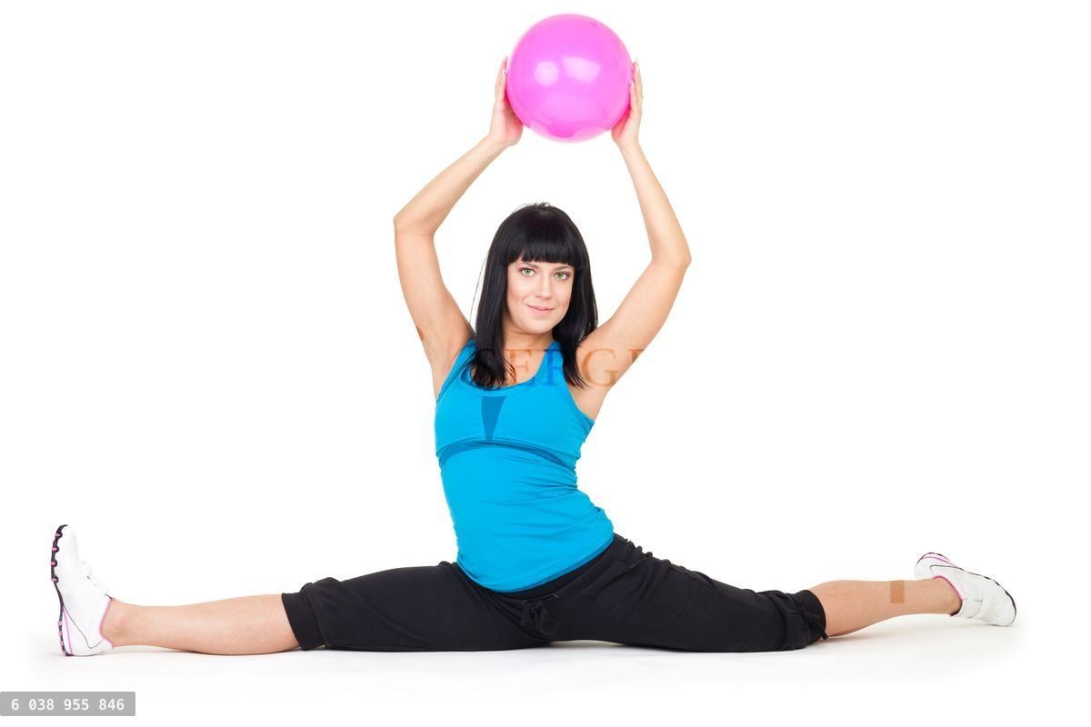 Woman do splits sitting holding ball