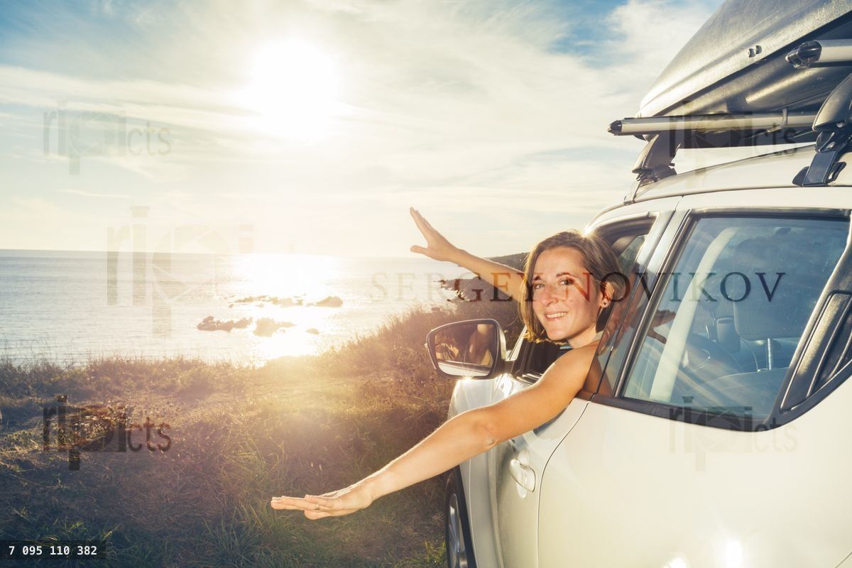 Woman smile look from car window on ocean sunset and wave hands