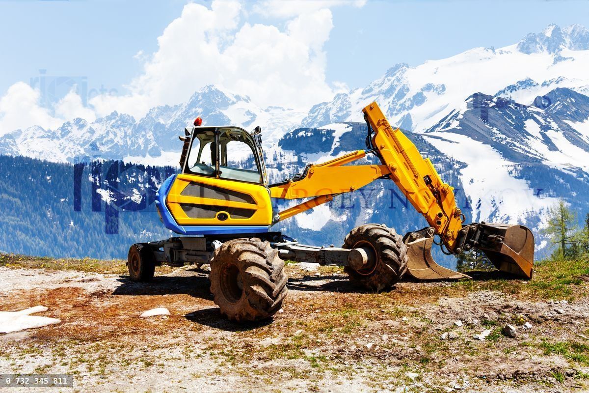 Yellow excavator working near mountains