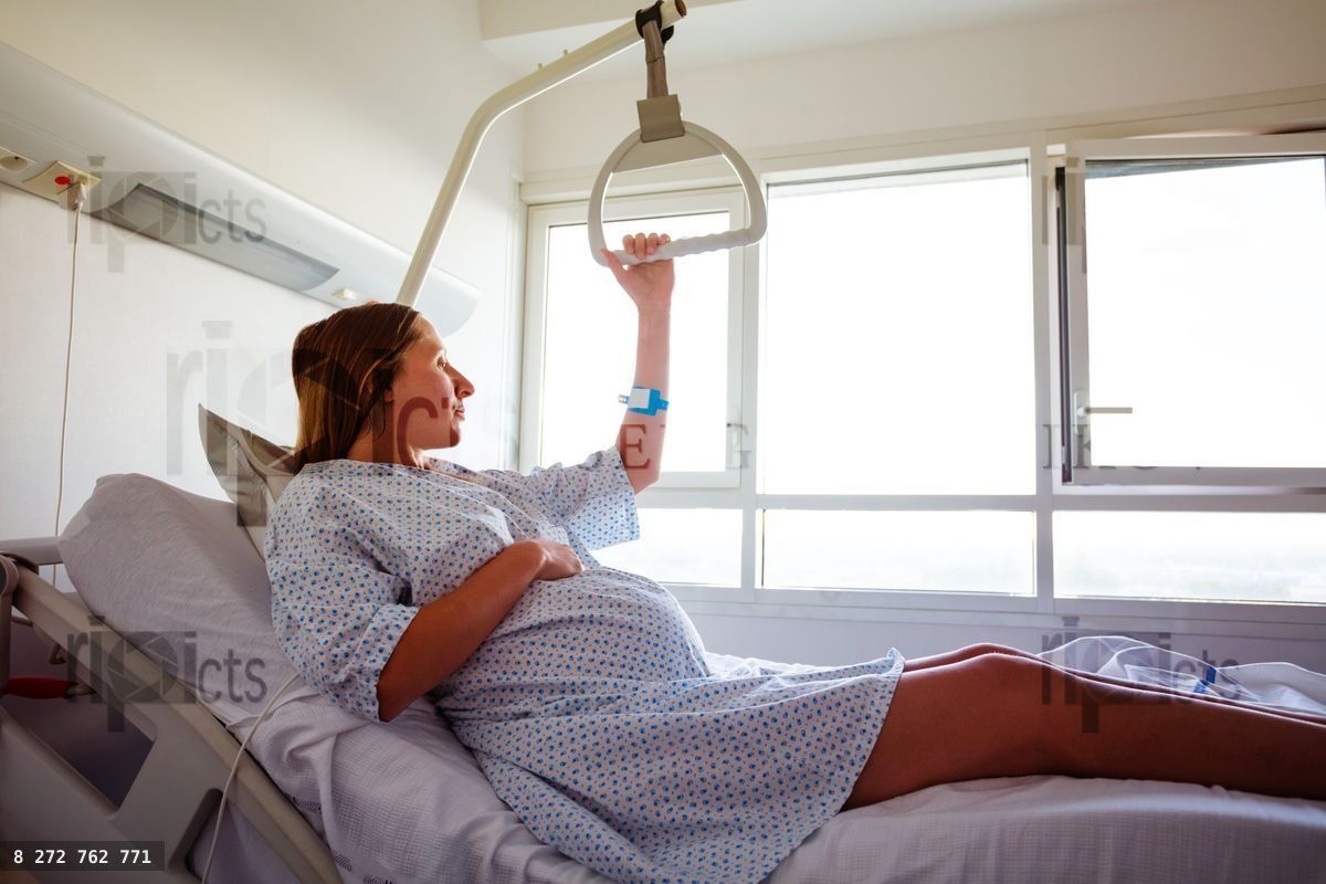 Woman lifting from hospital bed holding handle