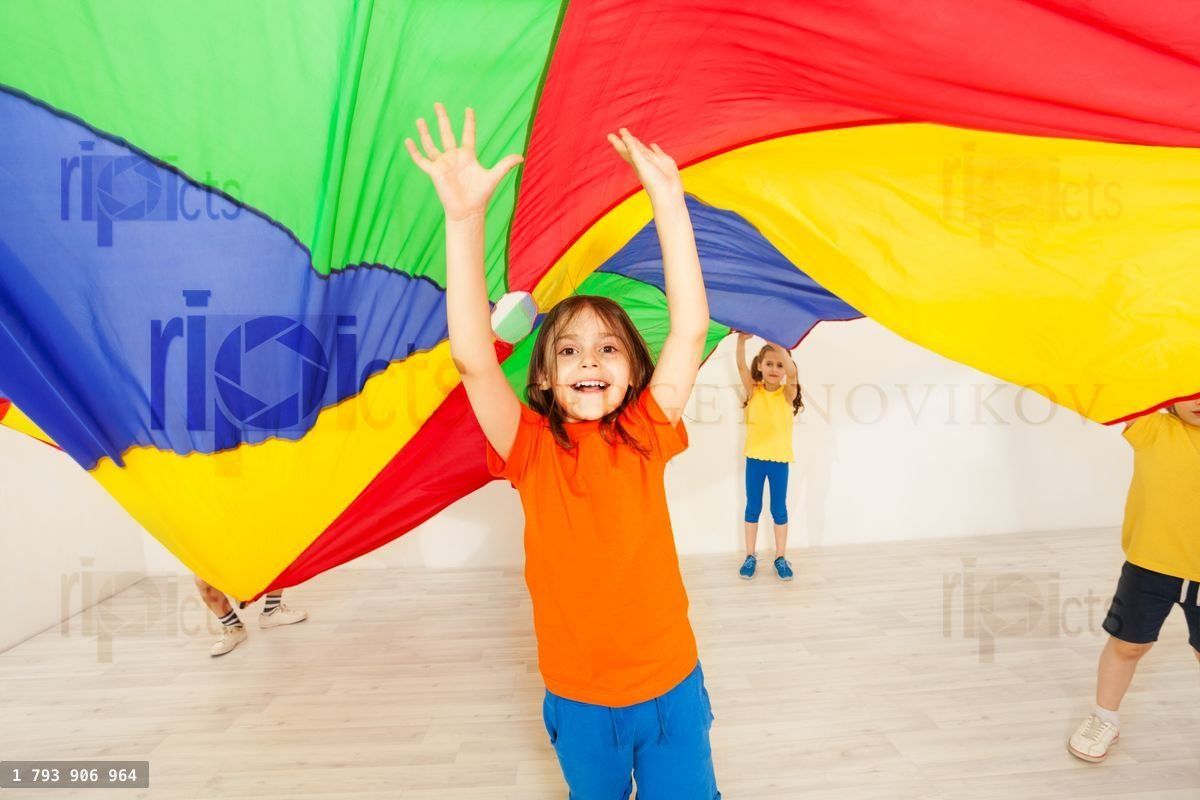 Girl hiding under parachute during sports festival