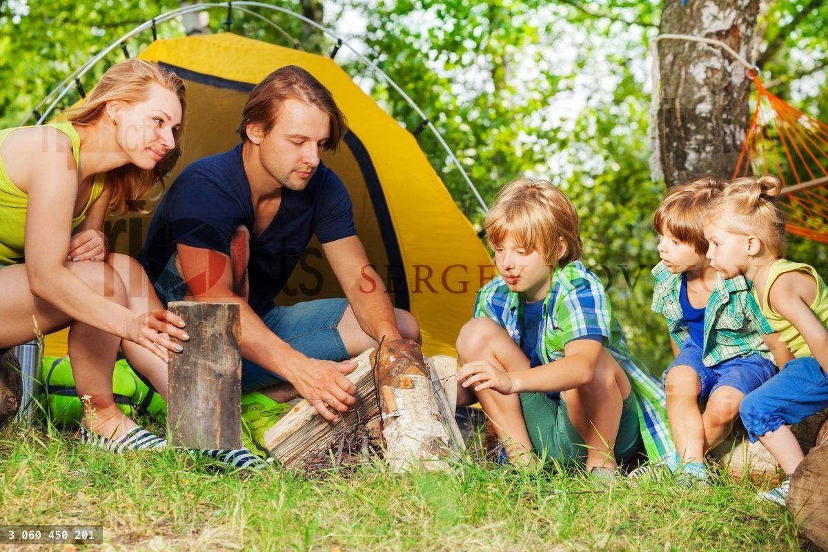 Young active family making camp fire in the woods