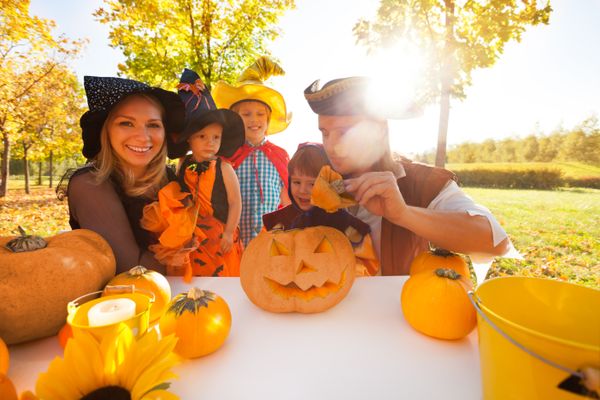 Family in Halloween costumes craft Jack O' Lantern