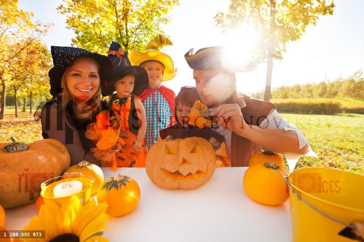 Family in Halloween costumes craft Jack O' Lantern