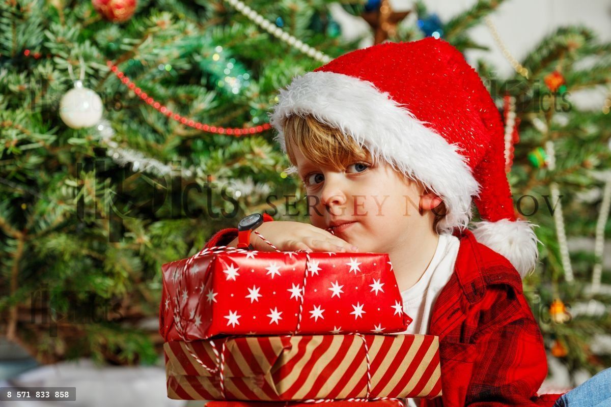 Portrait d'un enfant portant un bonnet de Père Noël célèbre Noël avec des cadeaux