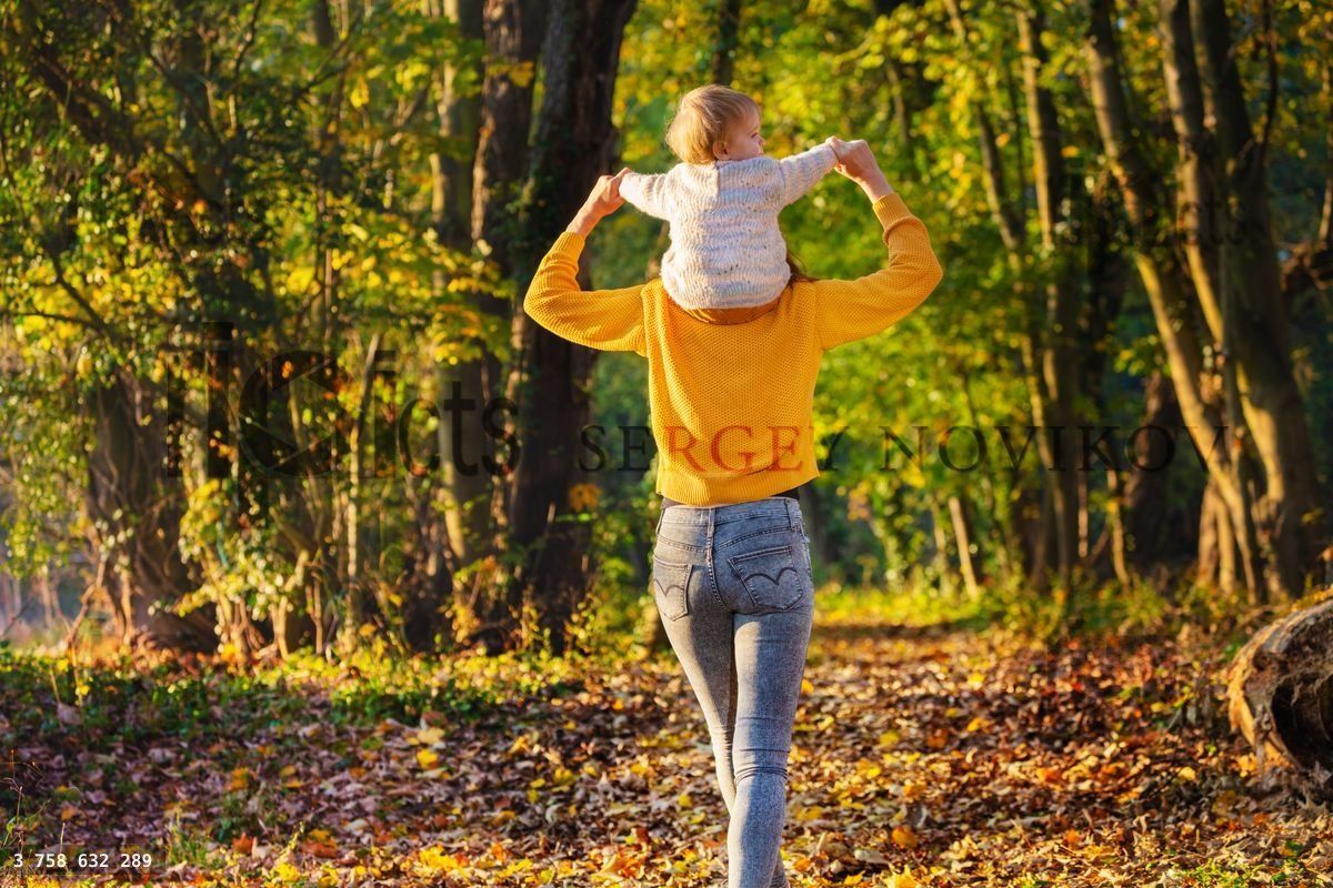 Woman walk with her kid on shoulders in forest