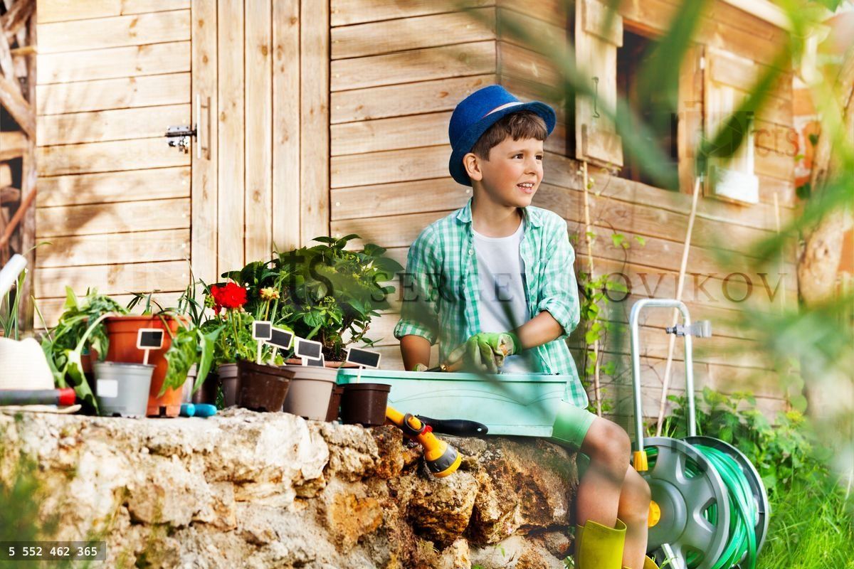 Funny little boy potting plants in the garden