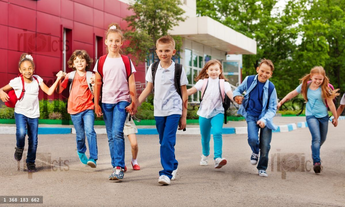 Row of happy kids with bags near school building