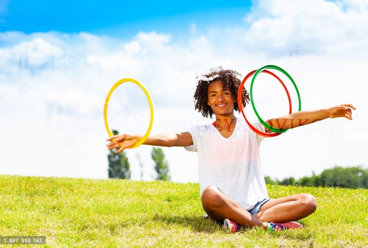 Young girl with curly hair rotate hoops in hands