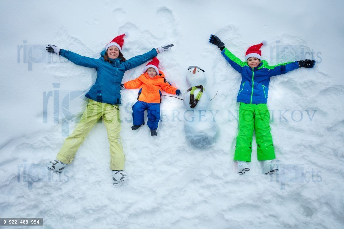 Family in snow together with snowman wear Santa hats top view