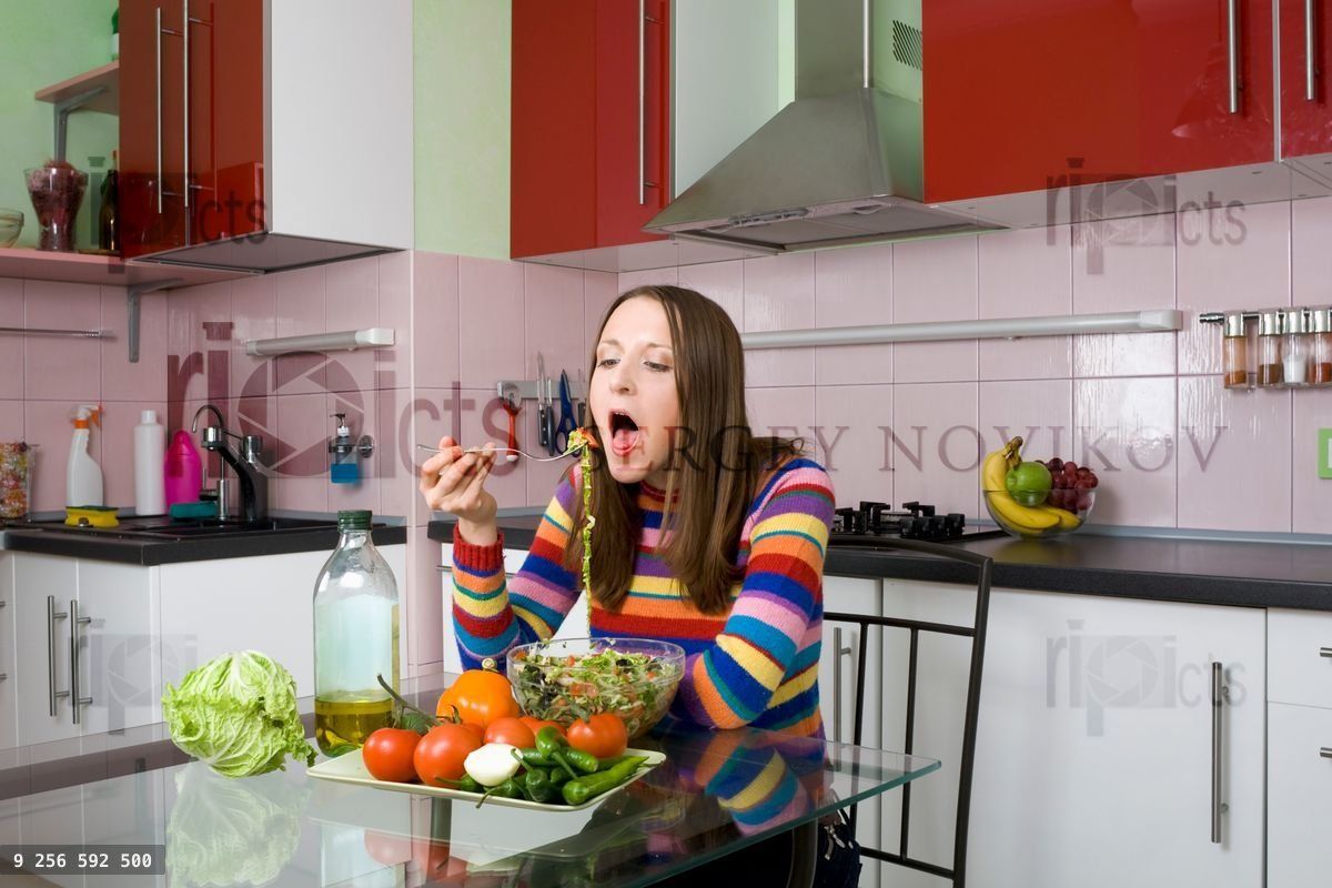 Woman eating salad in the kitchen