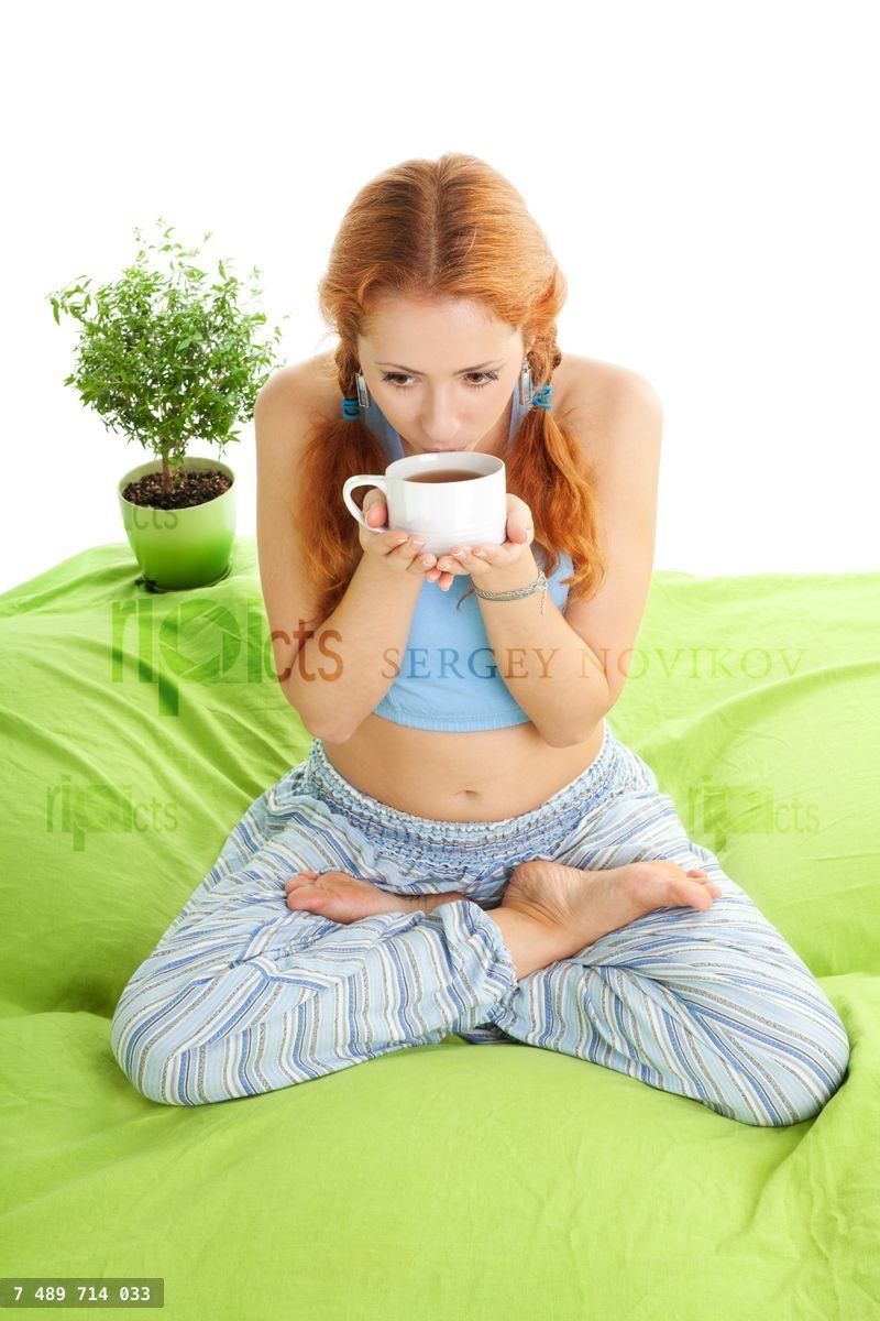 Young woman in yoga pose drinking tea