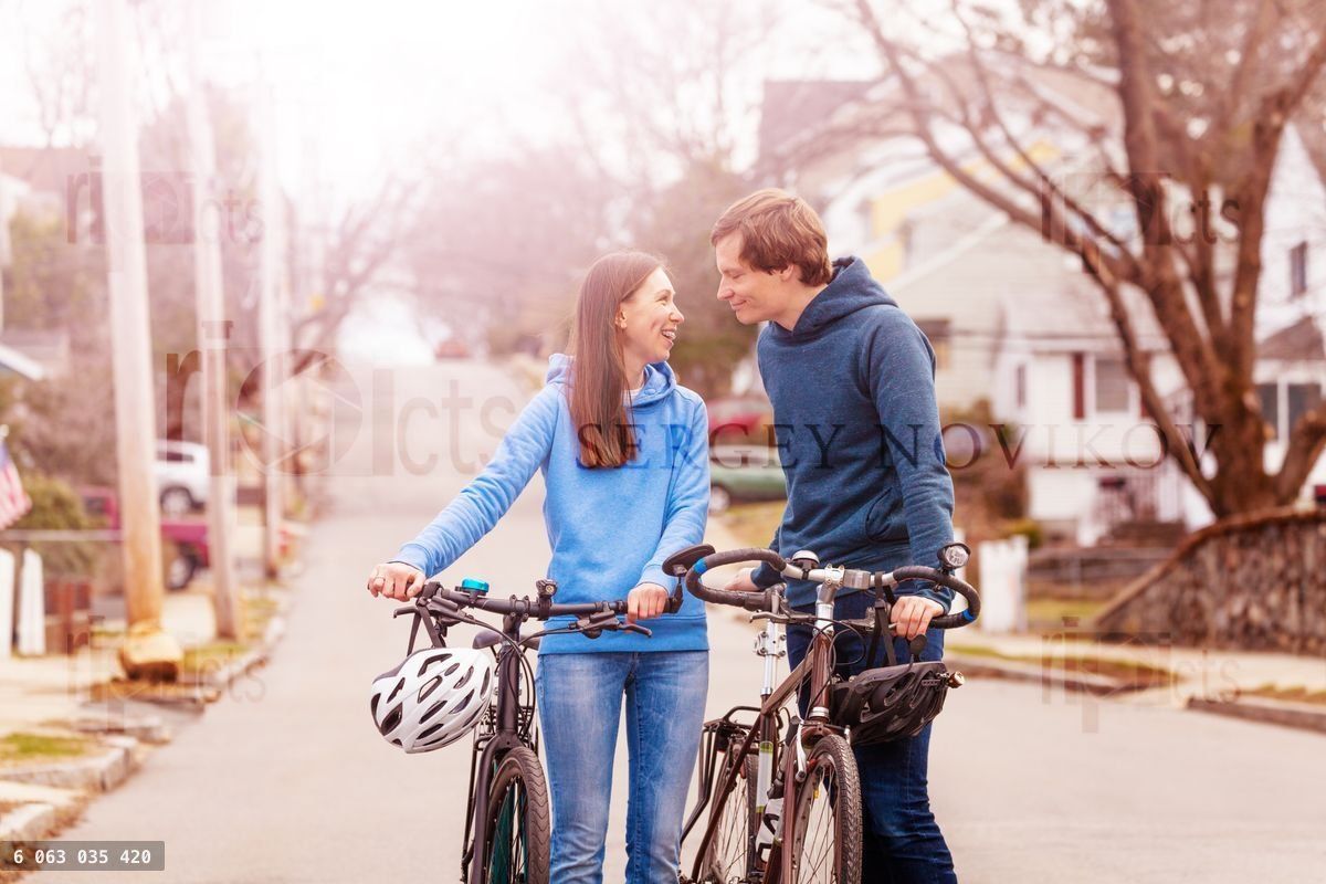 Young couple walk and closely holding bikes
