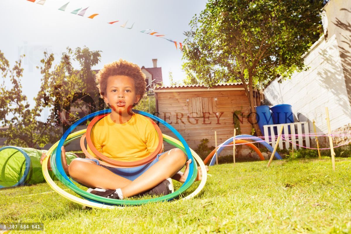 Happy black boy sit with hula rings on grass