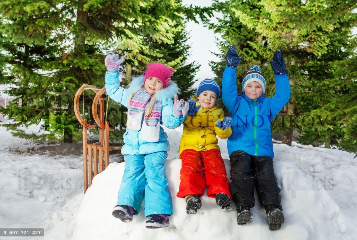 Groupe de petits enfants assis sur un mur de neige dans un parc