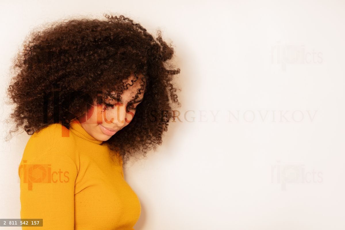 Young woman with curly hair looking down shy