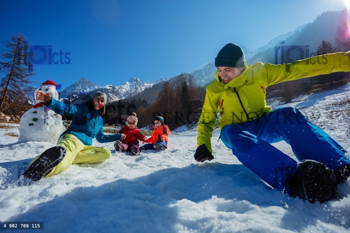 Young family enjoying snowy fun at mountain French resort
