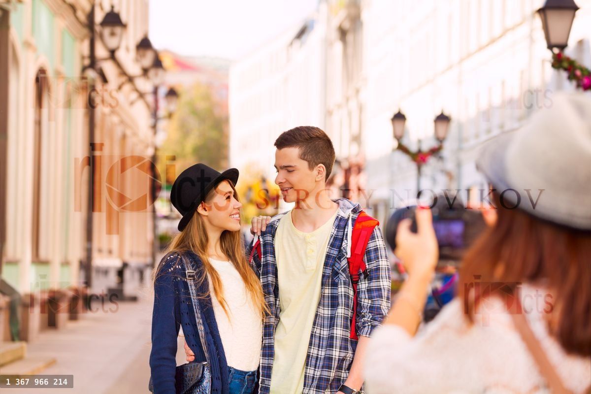 Garçon et femme se tiennent près et une fille les tire avec un appareil photo professionnel dans une rue européenne pendant la journée estivale