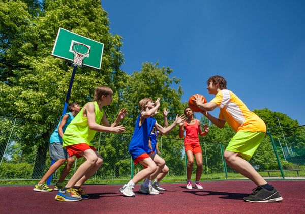 Teenage children playing basketball game together