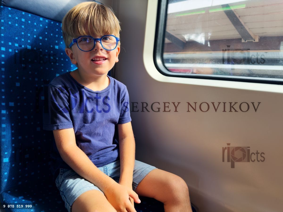 Young boy peers out train window while stopped at the platform