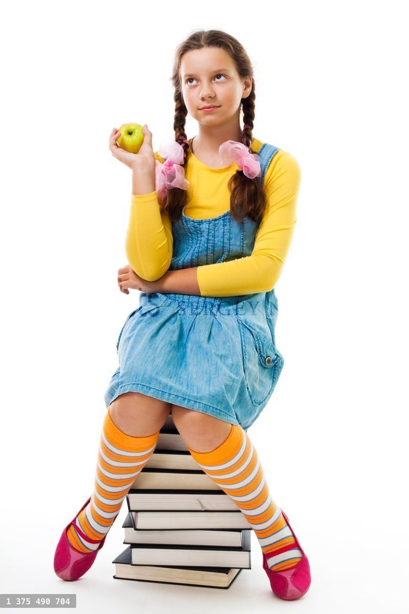Girl eat apple sitting on pile of books