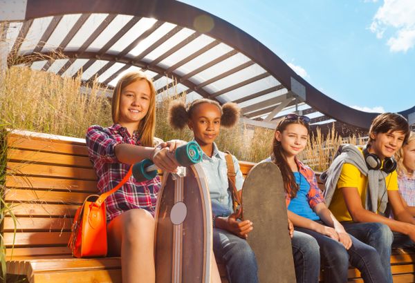 View of children who sit on wooden bench together