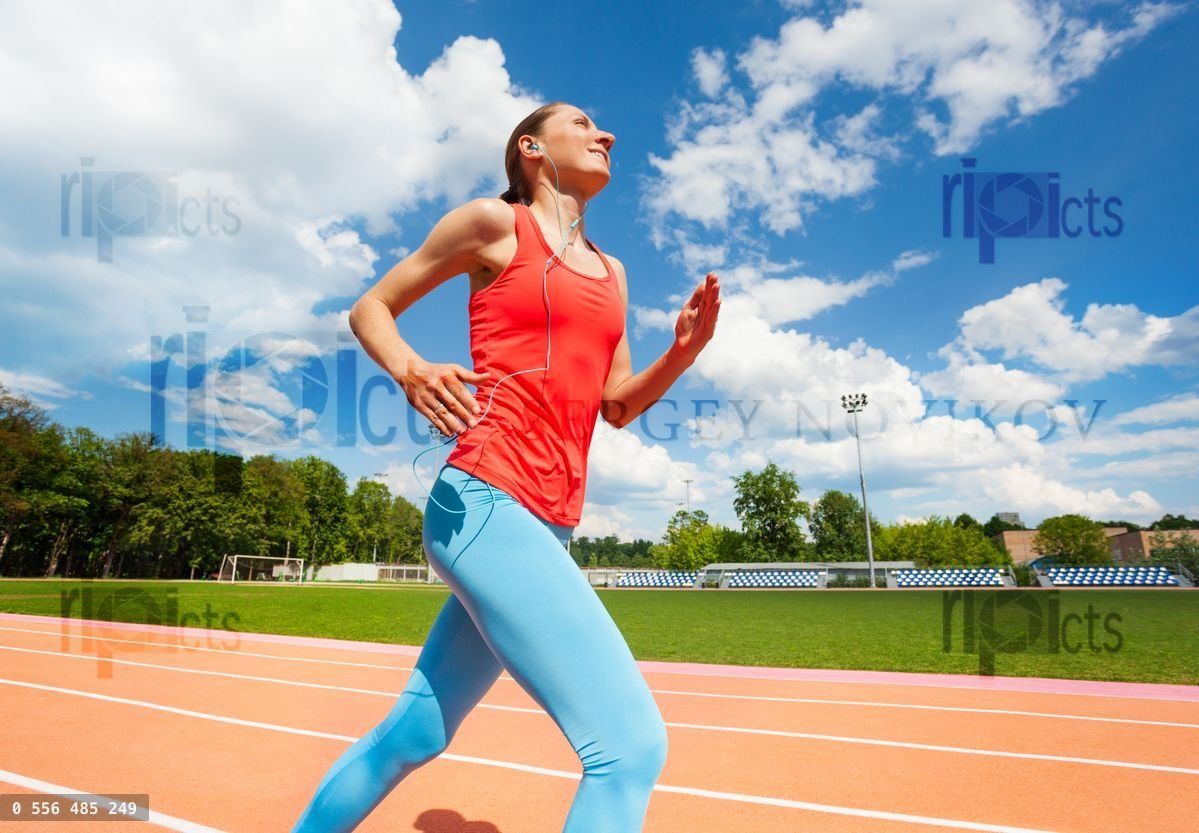 Woman listening music while running at the stadium