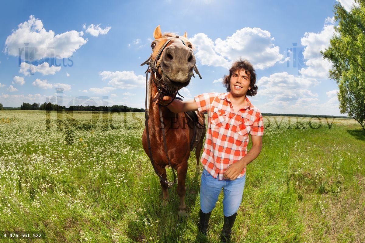 Young man holding his beautiful horse by a bridle