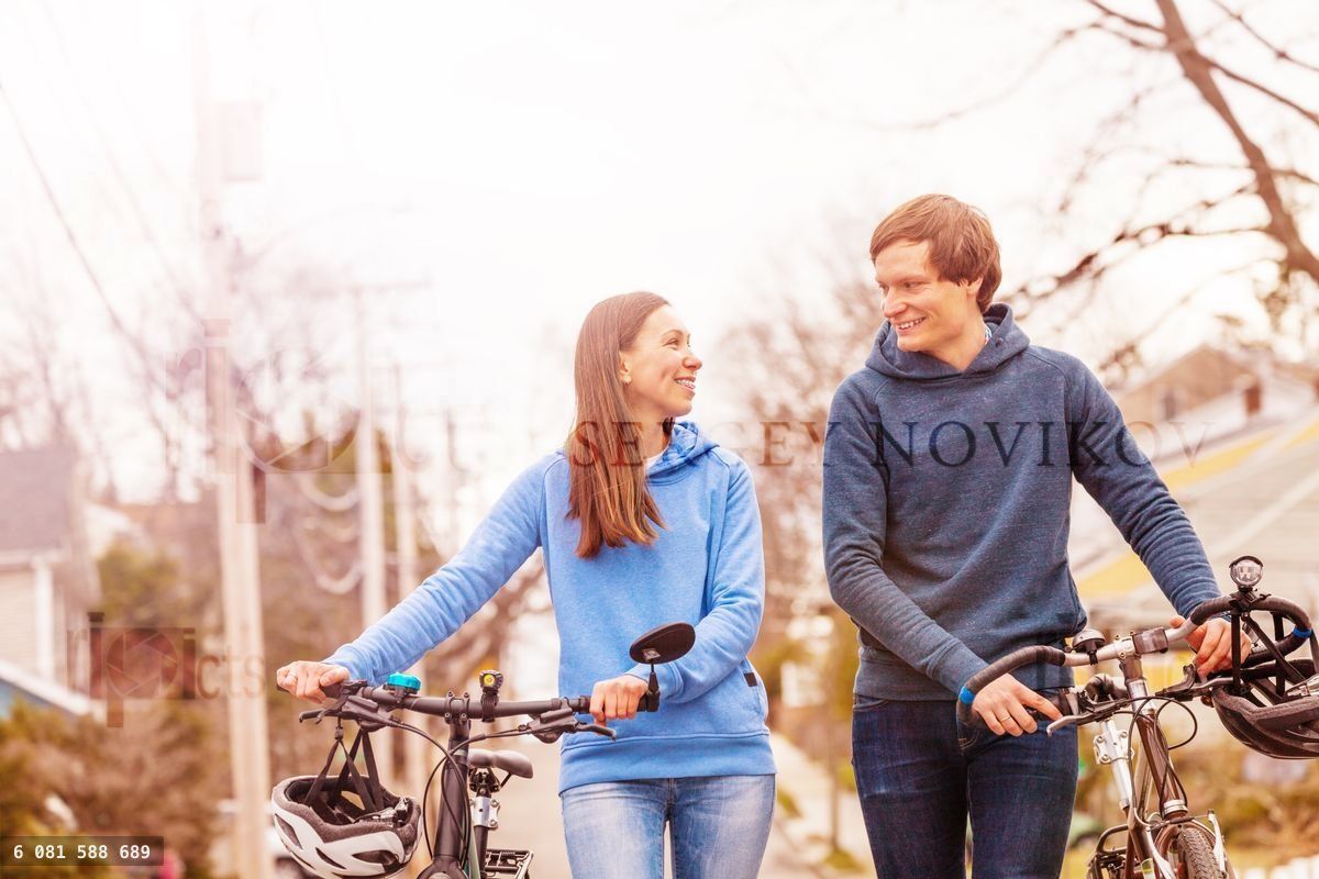 Young smiling couple walk with bicycles portrait