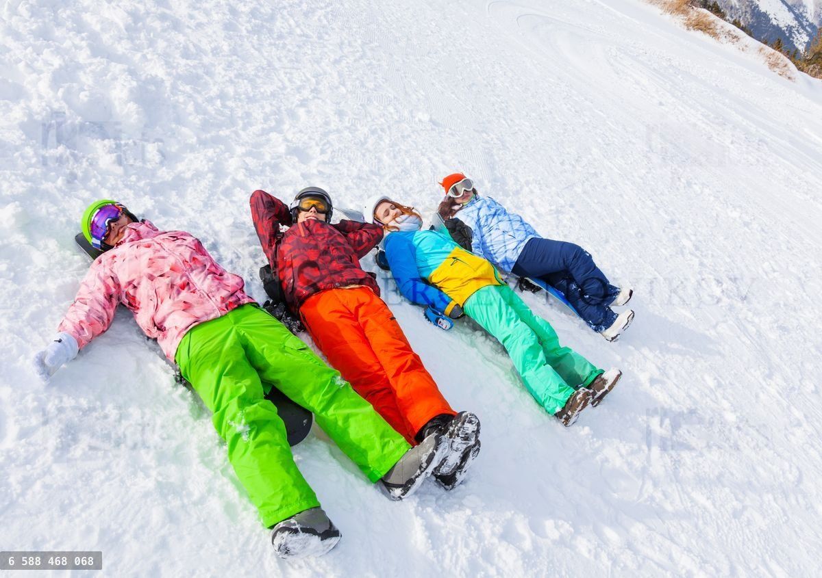 Four happy snowboarders lying in a row