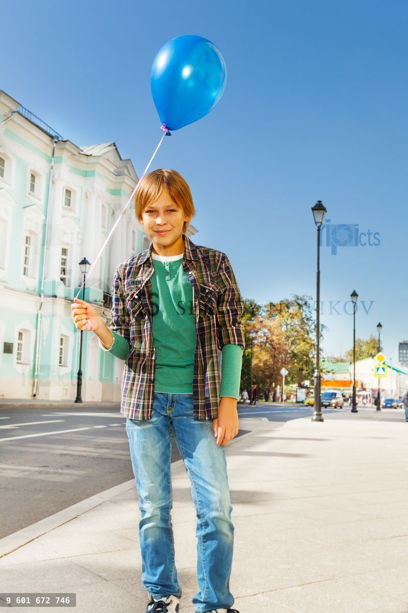 Boy with blue flying balloon standing on street