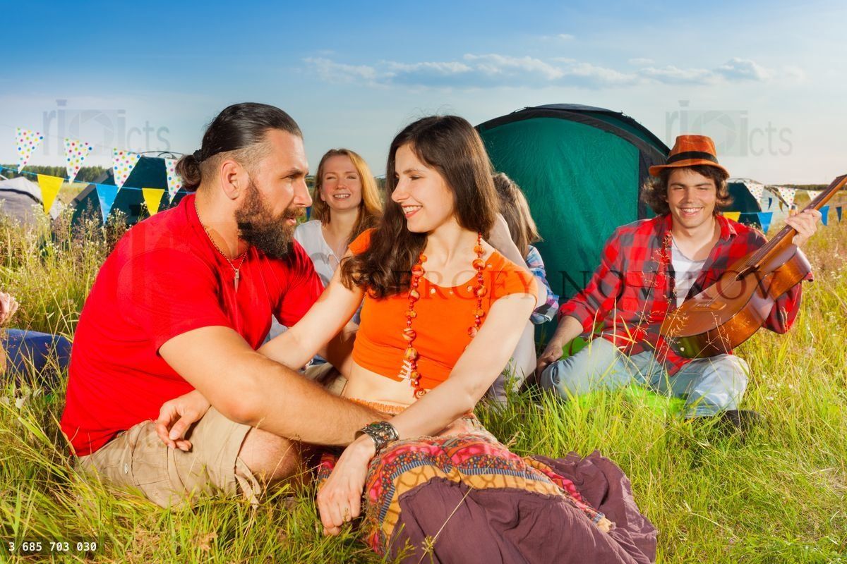 Young couple in love sitting on grass at campsite