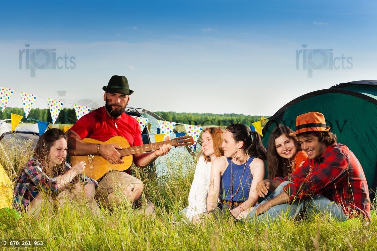 Friends enjoying music of guitar on camping trip