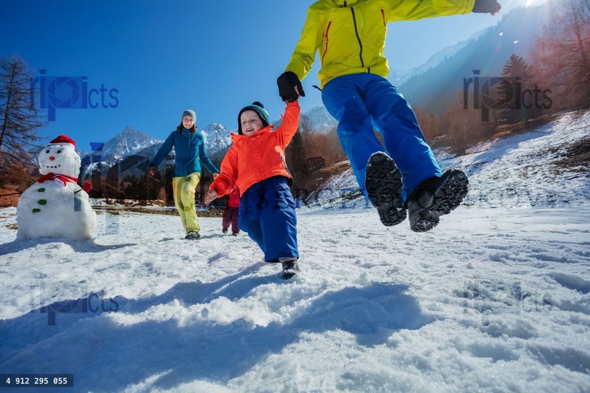 Family run and jump on snowy field over French Alpine resort