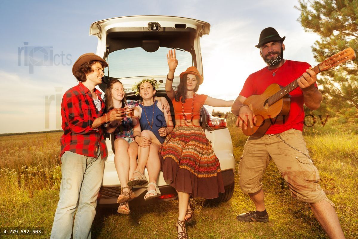 Funny young man playing guitar for his friends