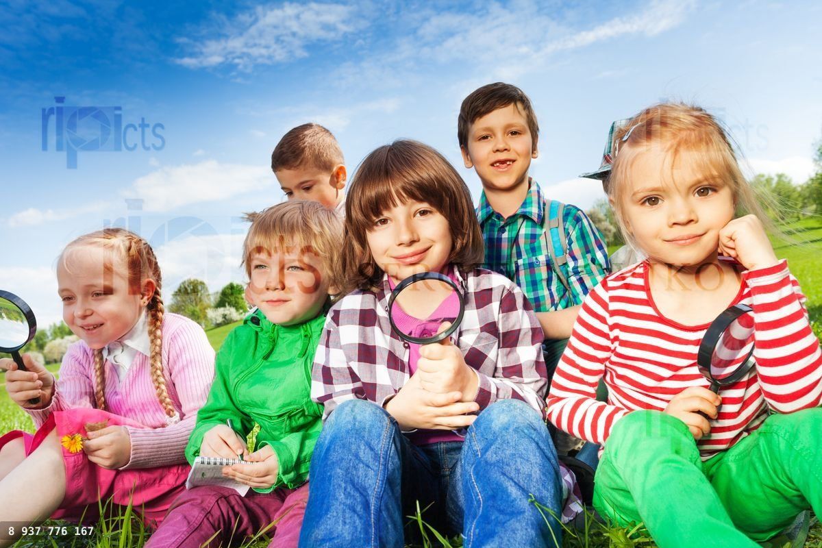 Cute children sitting on grass with magnifier
