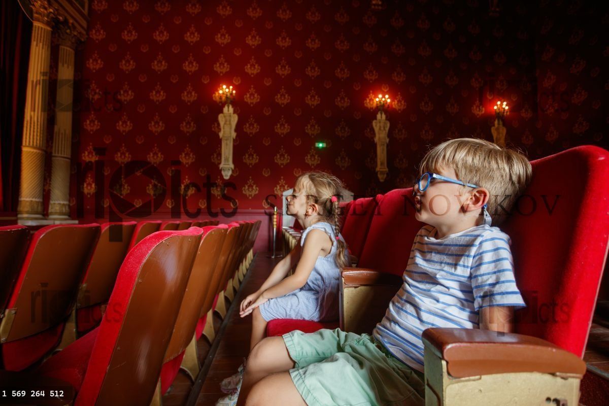 Young kids sit before theater stage, filled with anticipation