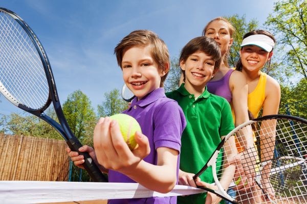 Family playing tennis holding rackets and ball