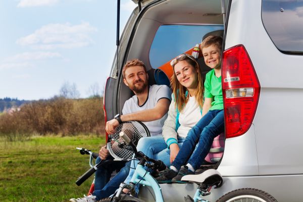 Happy sporty family sitting in the car boot