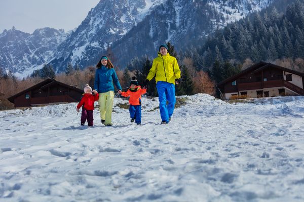 Family of four enjoys snowy mountain run and laugh hand in hand