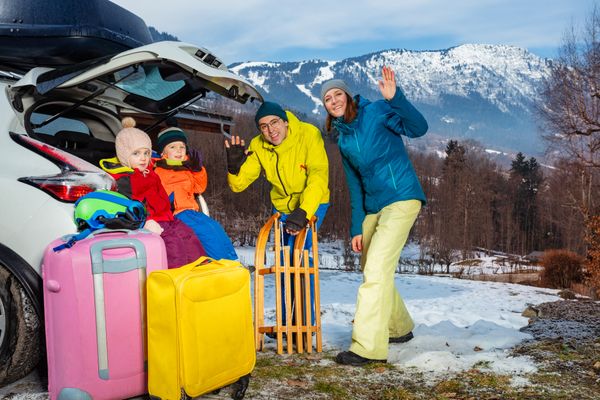 Family mom, dad, children unload baggage at winter destination