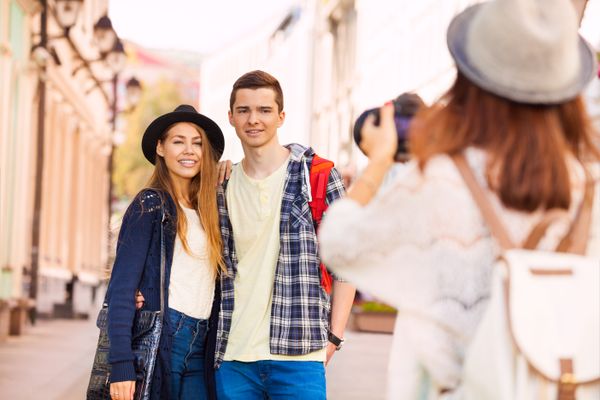 Boy and girl smiling with friend shooting them