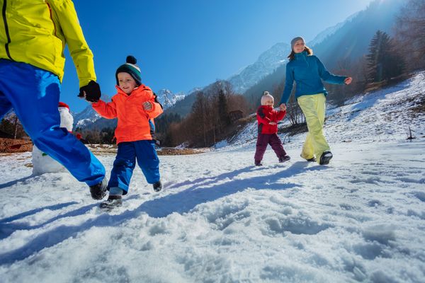 Parents run with small kid in mountains enjoy winter vacations