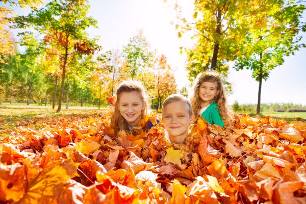 Kids having fun laying on the ground with leaves